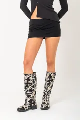Botas de cuero con estampado animal print de vaca en blanco y negro, con taco de 4cm y caña alta de 37cm.