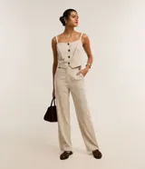 Pantalón recto de cintura alta, color beige con rayas verticales oscuras, bolsillos funcionales y detalle de aletas con botones en la cintura.