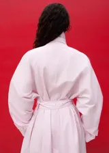 Chaqueta larga de algodón color rosado, de diseño recto con cuello solapa, manga larga, bolsillos laterales y cinturón tipo batín.