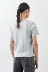 Remera de manga corta, cuello redondo y calce regular, color verde agua jaspeado. Presenta un pequeño parche bordado en la manga izquierda.
