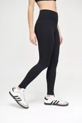 Calza deportiva negra con cintura alta y compresión media. Presenta una franja vertical blanca a lo largo de la pierna.