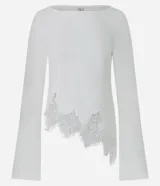 Blusa de algodón con cuello bote y mangas largas. Presenta un diseño asimétrico en el bajo decorado con un delicado detalle de encaje.