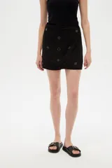 Short pollera negro de algodón y viscosa, de diseño holgado, con bordados decorativos y detalles metálicos en la cintura.