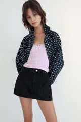 Falda pantalón de tiro medio confeccionada en tejido denim azul con costuras verticales decorativas, bolsillos delanteros y cierre frontal con cremallera y botón metálico.
