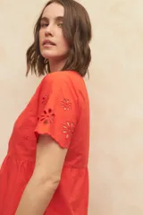 Vestido corto negro con escote redondo, mangas cortas con detalle de calado y falda escalonada con detalle de calado en el ruedo.