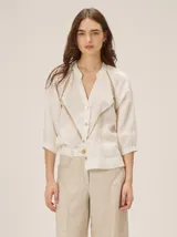 Camisa de lino color crudo con cuello en V, detalles de franjas transparentes en contraste y mangas tres cuartos abullonadas.