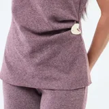 Sweater sin mangas color bordó melange, con cuello alto, diseño holgado y detalle de hebilla decorativa metálica en el lateral de la cintura.