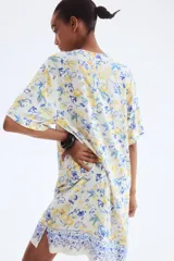 Vestido túnica a la rodilla en tejido liviano de viscosa con cuello mao y abertura en V. Modelo de corte holgado con hombros levemente caídos, mangas cortas y bajo recto con tajos laterales. Parte posterior algo más larga. Estampado de limones y flores azules.