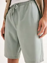 Bermuda de corte recto en color negro, confeccionada en tejido de algodón, con cierre frontal y bolsillos laterales.