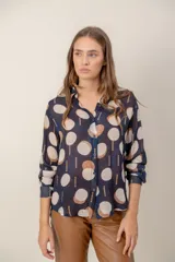 Camisa de manga larga con estampado de leopardo, cuello clásico y cierre frontal de botones. Presenta un corte holgado y puños abotonados.
