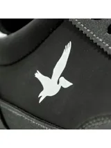 Championes deportivos Santa Barbara modelo Roam, de color blanco con detalles en gris claro y suela de goma marrón. Presentan el logotipo de la marca con la silueta de un ave en color negro en el lateral y cordones grises.