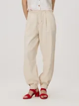 Pantalón tipo bombacha de campo color beige, de corte holgado con pinzas en la cintura y puños ajustados en los tobillos. Presenta costuras a contratono y bolsillos laterales.