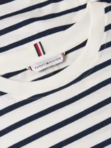 Remera de manga corta Tommy Hilfiger con diseño de rayas horizontales en azul marino y blanco. Presenta cuello redondo y el logo de la marca bordado en la manga.