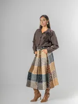 Falda midi de paño con estampa patchwork de inspiración escocesa, confeccionada en mezcla de lana. Presenta pinzas frontales, cintura elástica para mayor comodidad y un cinto desmontable a tono.