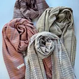 Pashmina rectangular con diseño a cuadros en tonos rosa y gris, con flecos en los bordes.