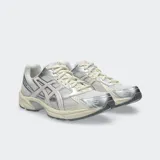 Championes Asics modelo Gel 1130, color blanco y plateado con detalles en negro, confeccionados con malla transpirable y revestimientos sintéticos, inspirados en el diseño de running de 2008 y equipados con tecnología GEL en el talón.