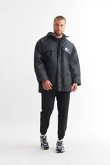 Campera negra impermeable con cuello alto, cierre frontal con botones a presión y múltiples bolsillos con solapa.