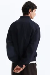 Campera bomber en mezcla de algodón y nylon color azul marino, con cuello elevado acanalado, cierre frontal, bolsillos laterales y un bolsillo con cierre en la manga.