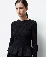 Remera de punto acanalado negro con ajuste al cuerpo, cuello redondo y mangas largas. Presenta un volado en la parte inferior confeccionado en lino, que aporta volumen y movimiento a la prenda.