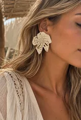 Aros grandes con diseño de flor en color marfil, con detalles perforados en los pétalos y centro texturizado.