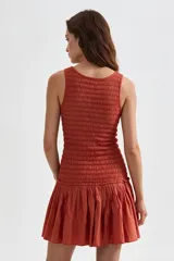 Vestido corto beige sin mangas con cuerpo de nido de abeja elástico y falda corta acampanada con vuelo.