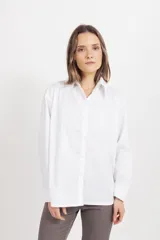 Camisa de corte clásico y diseño holgado, con cuello camisero, cierre frontal de botones y mangas largas con puños abotonados.