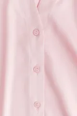 Blusa de manga larga color rosado pálido con acabado satinado. Presenta cuello clásico, escote en V con cierre de botones frontales y puños anchos.