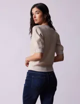 Cárdigan blanco tejido con escote en V, abertura frontal con botones y mangas cortas abullonadas con puño.