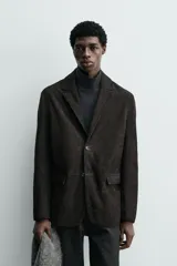 Blazer de corte regular confeccionado en piel con acabado de ante. Presenta cuello con solapas de muesca, cierre frontal de dos botones, bolsillos con solapa en la cadera y aberturas en la espalda.