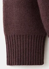 Jersey de punto color marrón oscuro, con cuello redondo y diseño oversize de manga larga.
