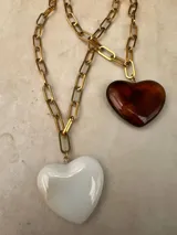 Collar de cadena de eslabones dorados con dije de corazón de resina pulida. Disponible en color blanco y color ámbar.