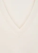 Buzo de punto fino en color blanco, con cuello en pico y manga larga. Presenta terminaciones en canalé en puños y ruedo.