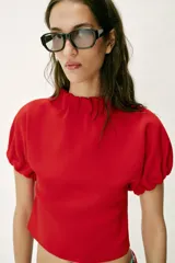Top de punto color azul marino, con cuello redondo y mangas cortas abullonadas con acabados elásticos fruncidos.