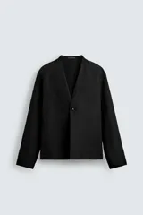 Blazer de corte relajado confeccionado en mezcla de algodón y lino. Presenta un diseño sin solapas, cierre frontal de un botón, manga larga y bolsillos ocultos en las costuras laterales. Interior sin forro.