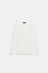 Jersey de punto fino negro con escote en V pronunciado, mangas largas y corte holgado con bajo asimétrico, más largo en la parte trasera.