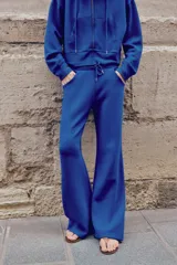 Pantalón flare de tiro medio, color azul, confeccionado en tejido de punto elástico. Cuenta con cintura elástica ajustable con cordón, bolsillos delanteros y corte amplio en las piernas.