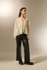 Blusa de poliéster color natural, con cuello en V, mangas largas con puños elásticos y detalle de frunces con cordón ajustable en el frente.