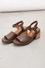 Sandalia de cuero marrón con diseño open-toe, tira ancha en el empeine, correa ajustable con hebilla en el tobillo y tacón ancho de madera.
