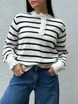 Sweater de punto a rayas horizontales blancas y negras, con cuello redondo, cierre frontal con botones y detalles de puntilla en el cuello y los puños.