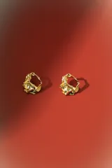Aros de diseño orgánico con textura irregular y acabado metálico plateado, con cierre de perno.