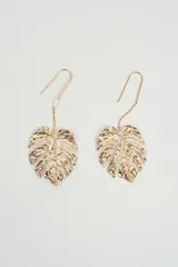 Aros colgantes con diseño de hoja tipo monstera, con acabado metálico dorado y gancho de sujeción.