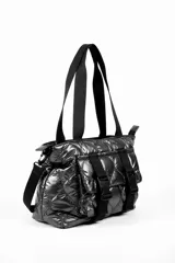 Cartera tipo tote bag color verde oscuro brillante, con diseño acolchado y correas negras. Presenta dos correas frontales con hebillas de plástico negras y un bolsillo frontal.