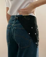 Bandana de encaje negro con forma triangular, decorada con apliques de estrellas espejadas y cierre de mosquetón metálico para enganchar en la cintura o usar en el cuello.
