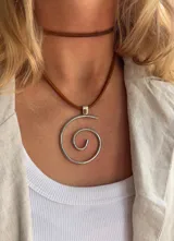 Collar con colgante circular de alpaca con diseño de espiral y cordón de cuero marrón.