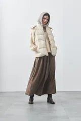 Chaleco puffer negro con diseño acolchado, capucha desmontable y cierre frontal. Cuenta con cordones ajustables en la cintura y bolsillos laterales.
