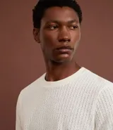 Remera de hombre color crudo, de punto calado con textura de encaje, cuello redondo y mangas cortas. Corte regular. Confeccionada en poliéster y algodón.