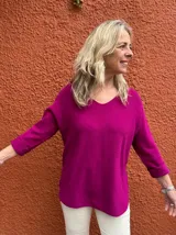Sweater de hilo color fucsia, de corte holgado, con escote en V y mangas largas con vuelta.