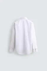Camisa de corte regular fit con cuello italiano y manga larga con puños abotonados. Presenta un diseño de rayas verticales finas en tono suave sobre fondo claro, con cierre frontal de botones.