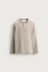 Jersey de punto relaxed fit confeccionado en hilatura con mezcla de algodón y cashmere, en color beige. Presenta cuello redondo con cierre frontal de botonadura y manga larga.