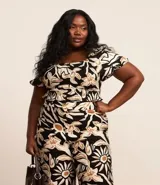Blusa de crepé con estampado floral en tonos beige y negro, escote recto y mangas cortas abullonadas con puños elásticos.